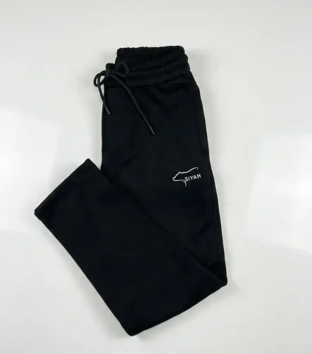 Side view of Siyah Onyx black fleece joggers showing the white bear-outline embroidery and ribbed ankle cuffs.